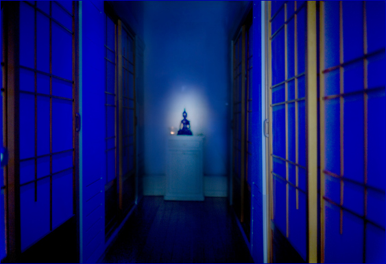 a welcoming hallway bathed in blue light at the end of which is a Buddha statue